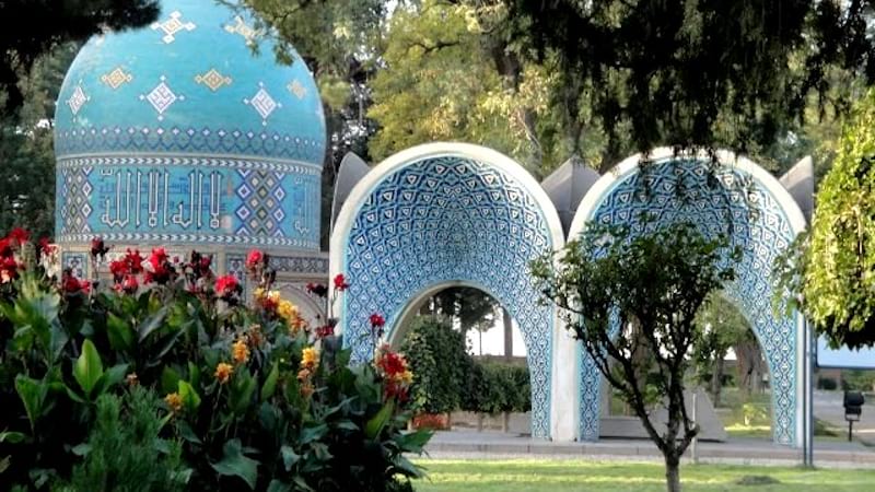 The courtyard surrounding the tomb of attar neishabouri is a tranquil space with a central pool and a garden filled with trees and flowers.